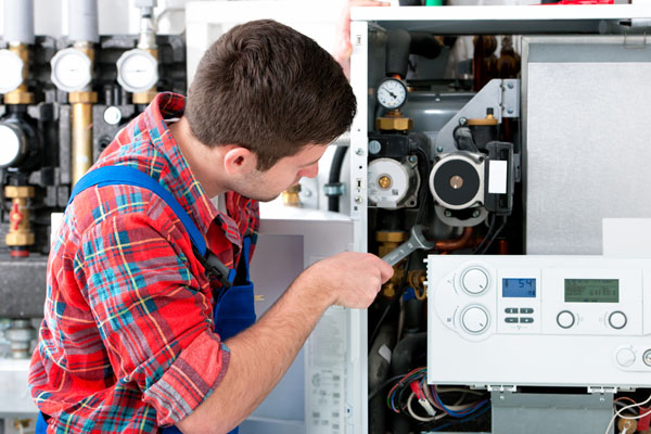 HVAC technician inspecting and repairing boiler controls in Pueblo